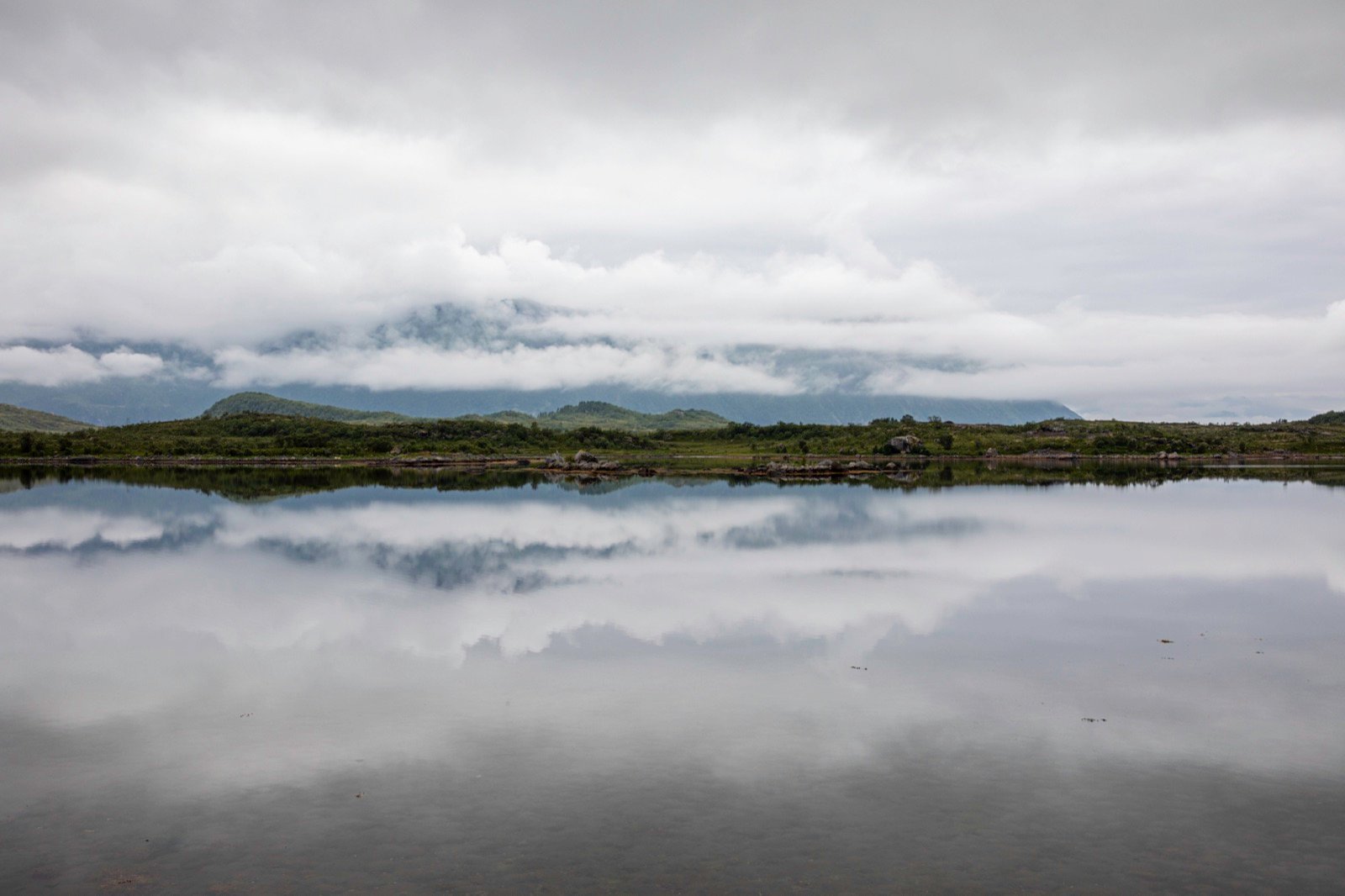 Still lake reflecting clouds and distant mountains in Norway
