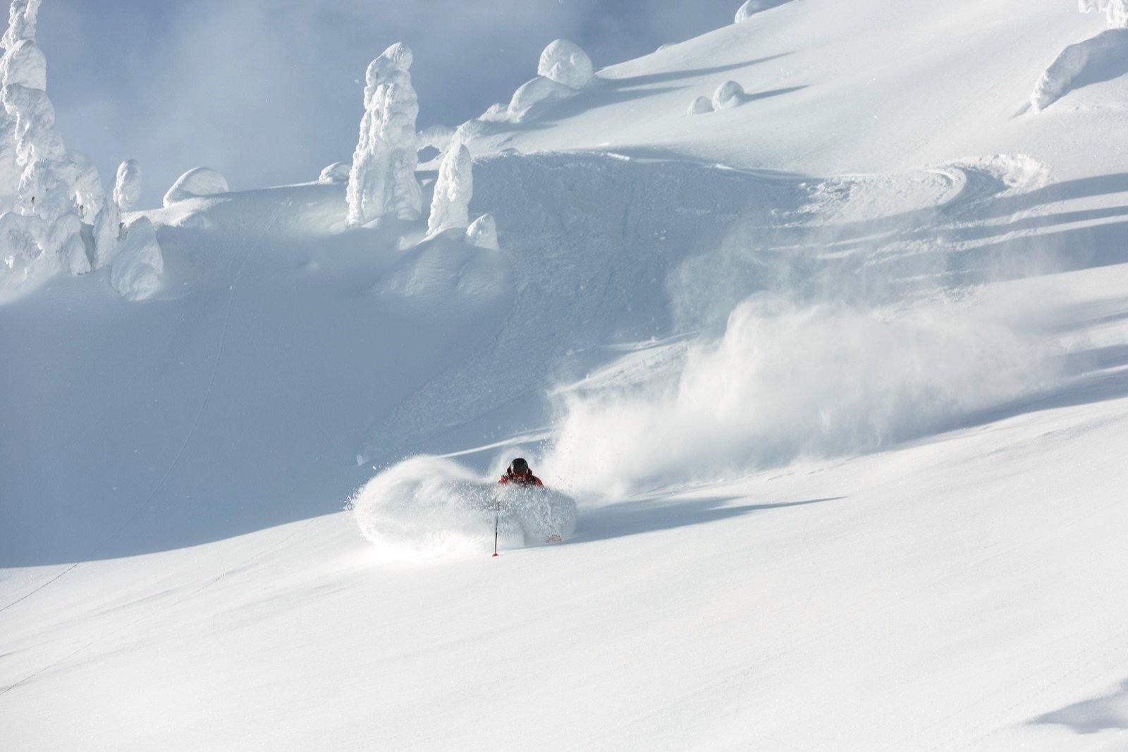 Skier erupting through deep powder at Keefer Lake Lodge, BC