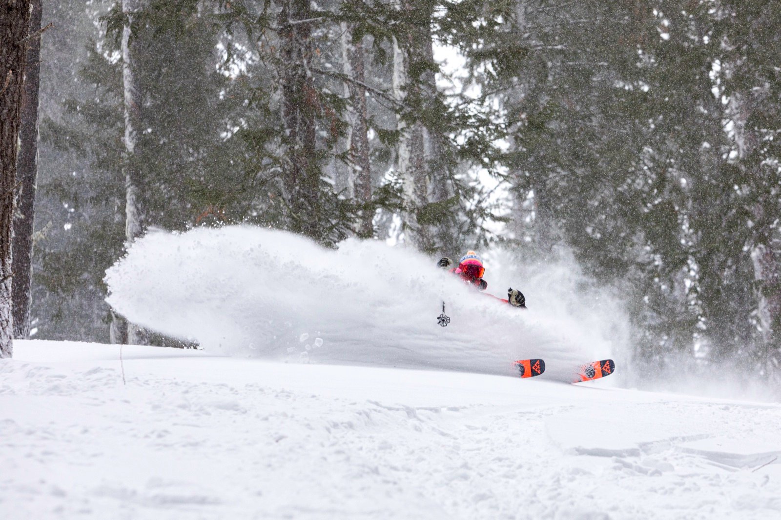 Skier spraying snow through a tight tree run at Keefer Lake Lodge, BC
