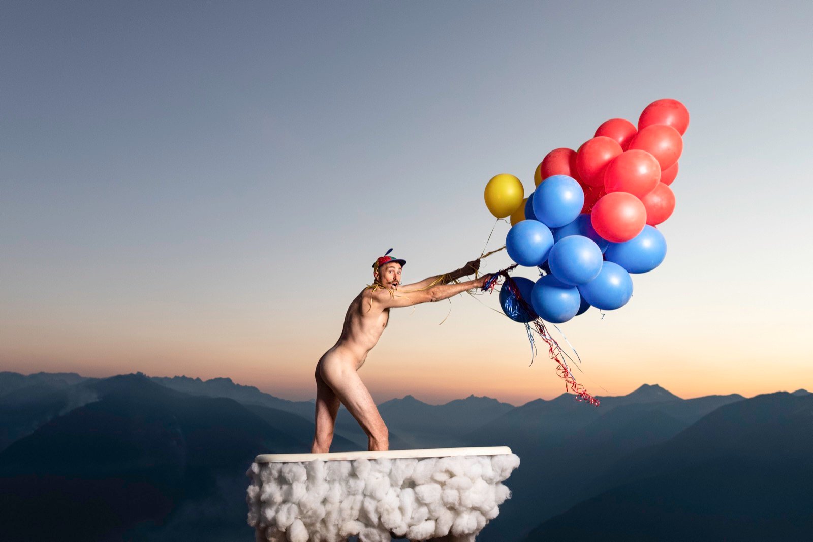 Silhouette holding balloons atop a mountain bathtub at sunset, Men in Tubs calendar